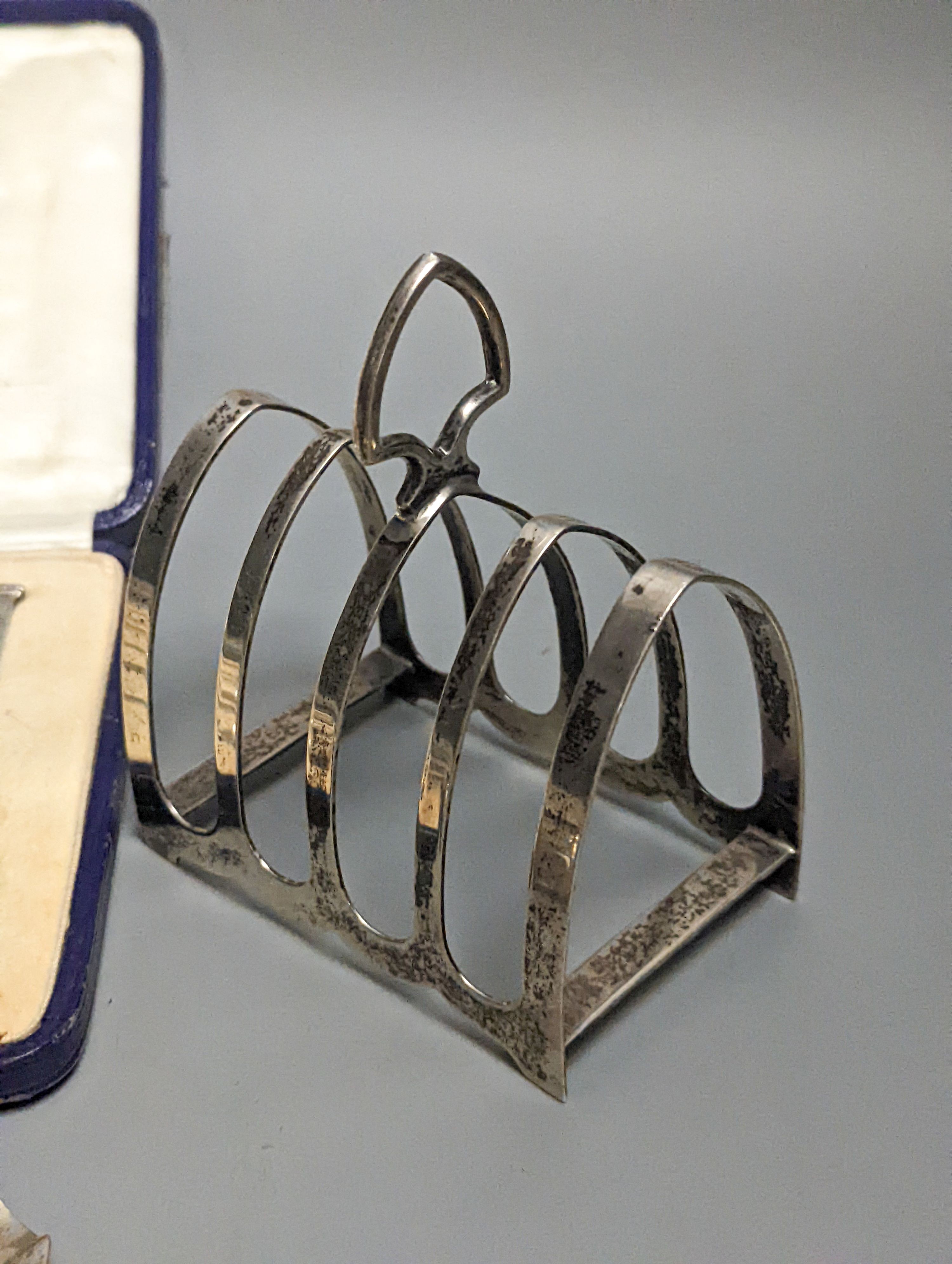 A pair of Edwardian glass handled silver salad servers, William Hutton & Sons, London, 1902, 26.8cm, a cased set of six silver teaspoons, a silver toastrack and a silver ashtray.
